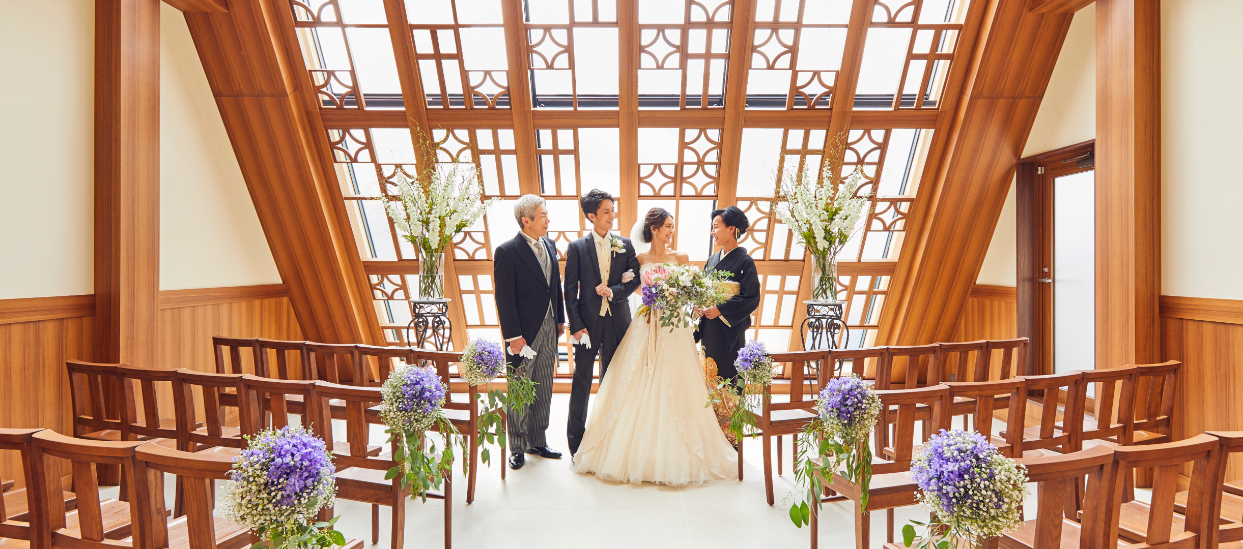 日差しの差し込むチャペルに立つ家族と新郎新婦